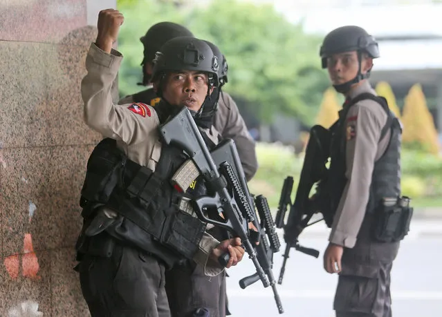 A police officer gives a hand signal to a squad mate as they search a building near the site of an explosion in Jakarta, Indonesia Thursday, January 14, 2016.  Attackers set off explosions at a Starbucks cafe in a bustling shopping area of downtown Jakarta and waged gun-battles with police Thursday, leaving bodies in the streets as office workers watched in terror from high-rise windows. (Photo by Tatan Syuflana/AP Photo)