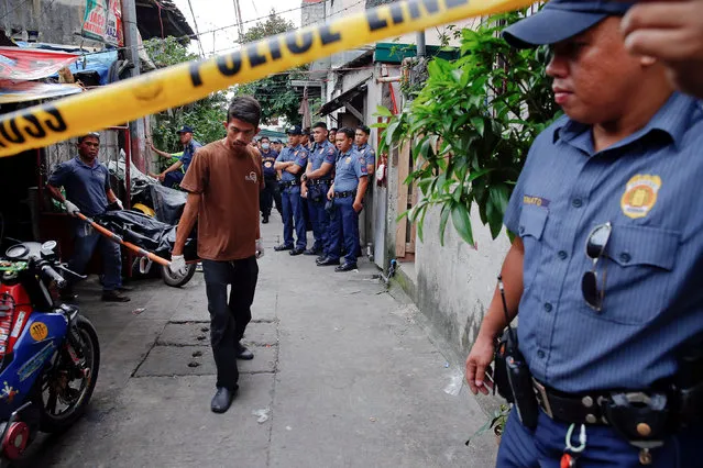 Police gather in an alley as the bodies of Noberto Maderal and fellow pedicab driver George Avancena, killed during a drug-related police operation, are taken by funeral parlour workers in Manila, Philippines October 19, 2016. (Photo by Damir Sagolj/Reuters)