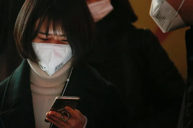 A woman wearing a face mask uses her phone while waiting for the bus on an extremely polluted day with red alert issued, in Langfang, Hebei province, China December 19, 2016. (Photo by Damir Sagolj/Reuters)