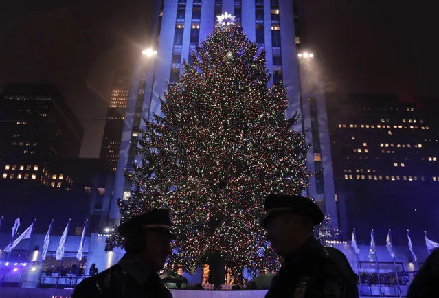 New York police officers stand across from the Rockefeller Center Christmas tree after the 84th annual Rockefeller Center Christmas tree lighting ceremony, Wednesday, November 30, 2016, in New York. The 94-foot tall Norway spruce is covered with 50,000 multicolored LED lights. (Photo by Julie Jacobson/AP Photo)