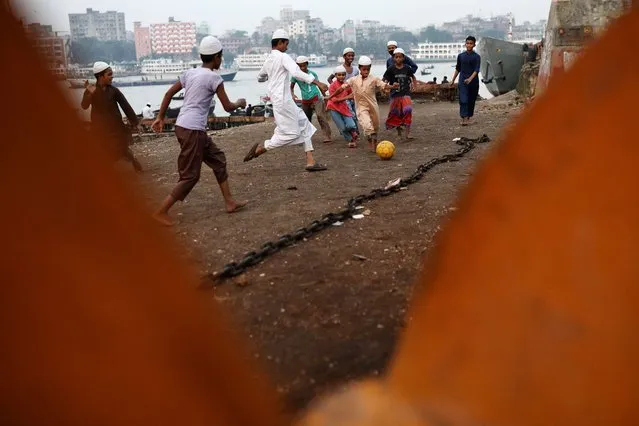 Children play football at dockyard premises in Dhaka, Bangladesh on October 9, 2023. (Photo by Mohammad Ponir Hossain/Reuters)