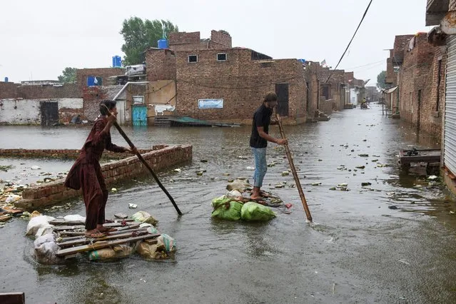 Men paddle on makeshift rafts as they cross a flooded street, amidst rainfall during the monsoon season in Hyderabad, Pakistan on August 24, 2022. (Photo by Yasir Rajput/Reuters)