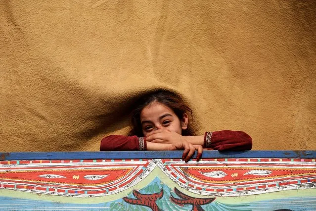 An Afghan refugee girl smiles onboard a truck while preparing to leave voluntarily for her home country as the government's deadline for expulsion approaches, at the UNHCR refugee camp and repatriation center in Nowshera, Pakistan, 30 October 2023. Pakistan's government ordered earlier this month all illegal immigrants, including almost 2 million Afghans, to leave the country by the end of October or face expulsion, after a surge in militant attacks, largely blamed on Afghan militants. (Photo by Arshad Arbab/EPA/EFE)