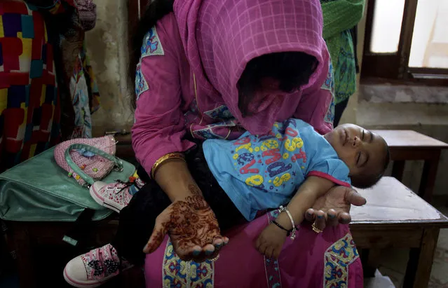 A Christian woman holds her child while she prays during Easter service at St. Oswald's Church in Lahore, Pakistan, Sunday, April 5, 2015. (Photo by K. M. Chaudary/AP Photo)