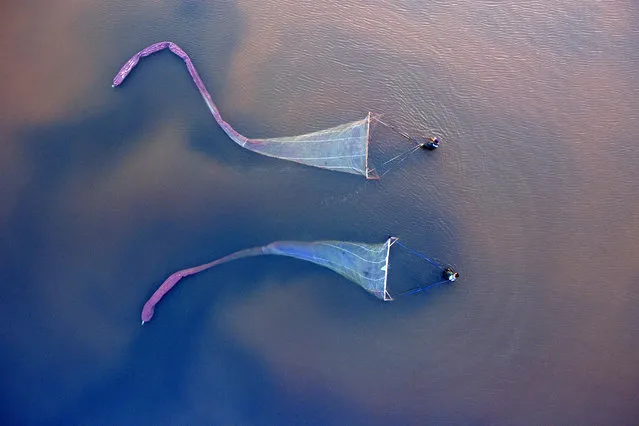 Two workers harvest brine shrimp in a salt lake near Shanxi, China on December 11, 2018. (Photo by Xinhua News Agency/Barcroft Images)