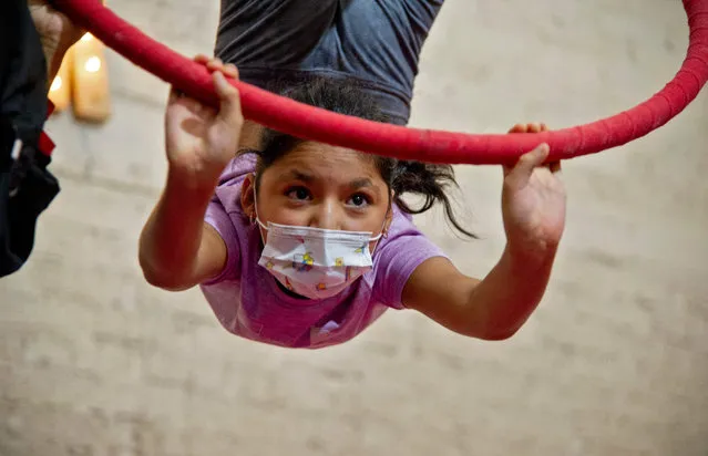 A girl practices at the “Lumina Cirkum” circus training space, in Atizapan de Zaragoza, Mexico State, on July 13, 2021. Children hang from hoops while aspiring acrobats balance on tightropes or spin in the air at a family circus school in Mexico, determined to keep their dreams alive despite the pandemic. (Photo by Claudio Cruz/AFP Photo)