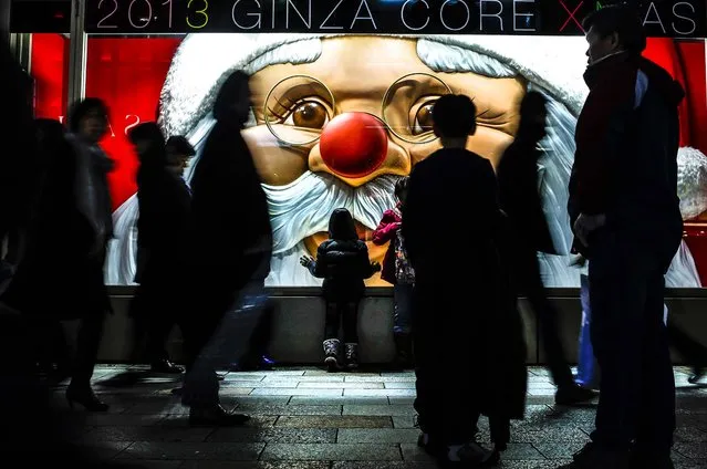 A child looks at a luxury brand store window with a Santa Claus display as people walk past at Ginza shopping district in Tokyo, on December 20, 2013. (Photo by Yuya Shino/Reuters)