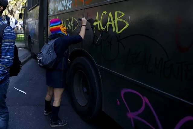 A student protester writes on a riot police bus during a demonstration against the government to demand changes in the education system at Santiago, April 16, 2015. (Photo by Ivan Alvarado/Reuters)