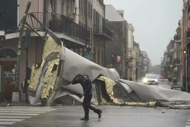 A man passes by a section of roof that was blown off of a building in the French Quaeter by Hurricane Ida winds, Sunday, August 29, 2021, in New Orleans. (Photo by Eric Gay/AP Photo)