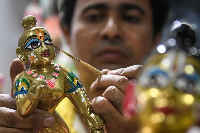 An artist gives finishing touches to an idol of Hindu deity Lord Krishna at a workshop in Amritsar on August 25, 2021 ahead of the “Janmashtami” festival which is celebrated to mark the birth of Krishna. (Photo by Narinder Nanu/AFP Photo)