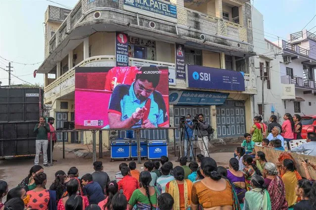 Villagers cheer as they watch the live telecast of the women's singles table tennis (class 4) match between India's Bhavinaben Patel and China's Ying Zhou at the Tokyo 2020 Paralympic Games on a large screen installed at a street intersection in the village Sundhia, about 100 kms from Ahmadabad on August 29, 2021. (Photo by Sam Panthaky/AFP Photo)