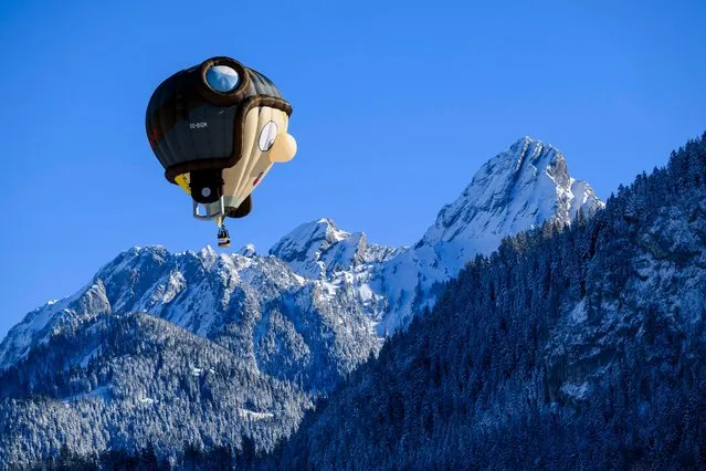 A hot-air balloon flies over the Swiss Alps during the 44th International Hot Air Balloon Festival in Chateau-d'Oex, Switzerland, Saturday, January 20, 2024. (Photo by Jean-Christophe Bott/Keystone via AP Photo)