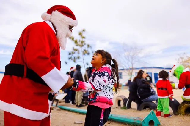 Sheyla Alvarez, a migrant girl from Honduras, who lives with her family in a shelter while they wait to apply for asylum in the U.S., after the Supreme Court said Title 42 should stand as is for now, speaks with a man dressed as Santa Claus during a Christmas celebration, in Ciudad Juarez, Mexico on December 25, 2022. (Photo by Jose Luis Gonzalez/Reuters)