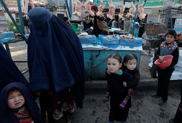 A mother shops with her children at the market in Kabul, Afghanistan on October 29, 2021. (Photo by Zohra Bensemra/Reuters)