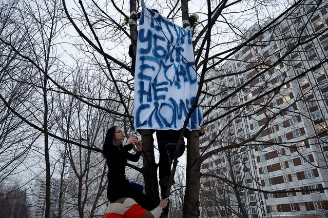 People attach a banner to a tree near the Borisovskoye cemetery after the funeral of Russian opposition politician Alexei Navalny, in Moscow, Russia, on March 1. A slogan on the banner refers to Russian President Vladimir Putin and reads: “Putin killed him but didn't break (his spirit)”. (Photo by Reuters/Stringer)