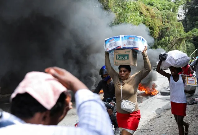 People react as they walk near a burning barricade set up in protest against the government and calling for the resignation of Prime Minister Ariel Henry, in Port-au-Prince, Haiti on February 5, 2024. (Photo by Ralph Tedy Erol/Reuters)