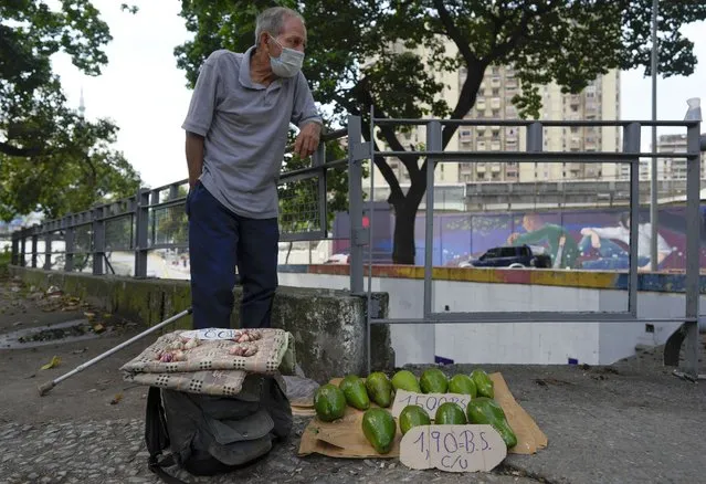 Rafael Rojas sell avocados and garlic on a street in Caracas, Venezuela, Friday, October 1, 2021. (Photo by Ariana Cubillos/AP Photo)