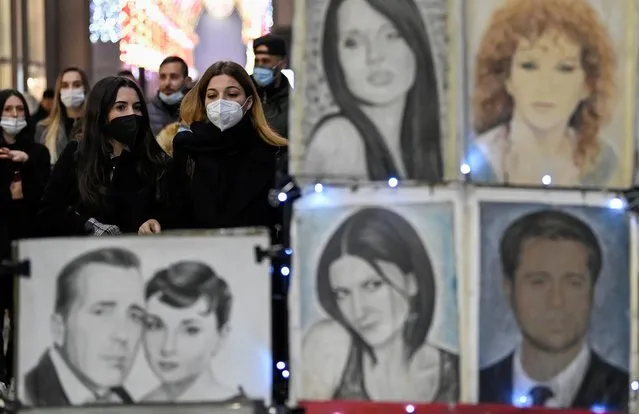 People wearing face masks walk near portrait drawings amid the coronavirus disease (COVID-19) pandemic in Milan, Italy, November 28, 2021. (Photo by Flavio Lo Scalzo/Reuters)