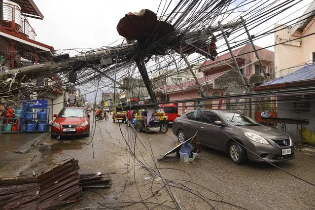 Cars pass by a toppled electrical post due to Typhoon Rai in Surigao city, Surigao del Norte, southern Philippines as power supply remain down on Sunday December 19, 2021. The death toll in the strongest typhoon to batter the Philippines this year continues to rise and the governor of an island province especially hard-hit by Typhoon Rai said there may be even greater devastation that has yet to be reported. (Photo by Jilson Tiu/AP Photo)