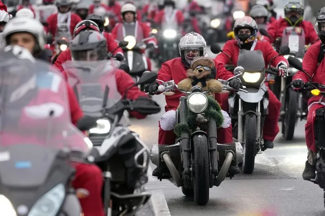Bikers wearing Santa Claus costumes ride their bikes during a Santa Claus parade as they travel to a children's hospital to deliver toys to patients in Belgrade, Serbia, Sunday, December 26, 2021. (Photo by Darko Vojinovic/AP Photo)