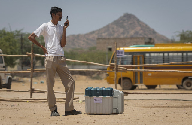 A polling officer stands next to Voter Verifiable Paper Audit Trail (VVPAT) and Electronic Voting Machines (EVM) as he waits for his colleagues at a distribution centre, ahead of the second phase of the general elections, in Barmer in the desert state of Rajasthan, India, on April 25, 2024. (Photo by Adnan Abidi/Reuters)