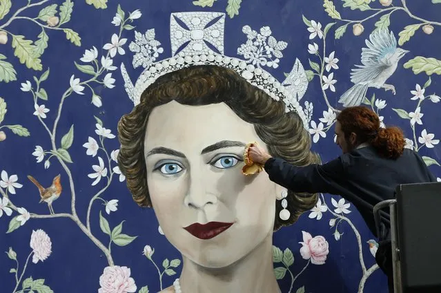 Workmen install a new mural by Frederick Wimsett, of Britain's Queen Elizabeth II to mark her 90th birthday celebrations, in central London, Tuesday, April, 19, 2016. The longest-reigning monarch in British history turns 90 on Thursday. (Photo by Alastair Grant/AP Photo)