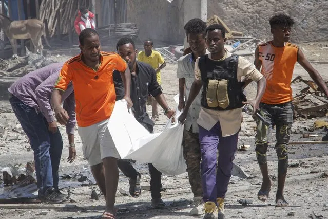 Rescuers carry away the body of a civilian who was killed in a blast in Mogadishu, Somalia, Wednesday, January 12, 2022. A large explosion was reported outside the international airport in Somalia's capital on Wednesday and an emergency responder said there were deaths and injuries. (Photo by Farah Abdi Warsameh/AP Photo)