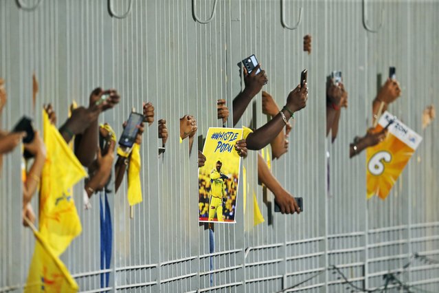 Fans carry a poster of Chennai Super Kings' MS Dhoni and take pictures through a fence as they wait for the Indian Premier League cricket match between Chennai Super Kings and Punjab Kings to begin in Chennai, India, Wednesday, May 1, 2024. (Photo by R. Parthibhan/AP Photo)