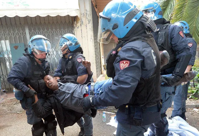 Italian police officers remove a migrant in Ventimiglia, at the Italian-French border Tuesday, June 16, 2015. Police at Italy's Mediterranean border with France have forcibly removed some of the African migrants who have been camping out for days in hopes of continuing their journeys farther north. The migrants, mostly from Sudan and Eritrea, have been camped out for five days after French border police refused to let them cross. (Luca Zennaro/ANSA via AP)