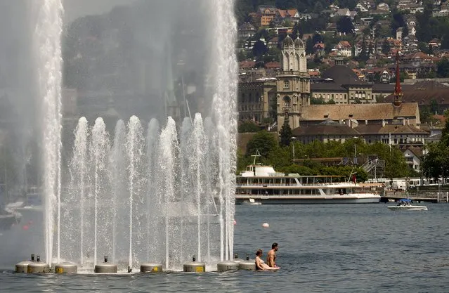 A couple relaxes during hot temperatures beside a fountain in Lake Zurich in Zurich July 3, 2015. (Photo by Arnd Wiegmann/Reuters)