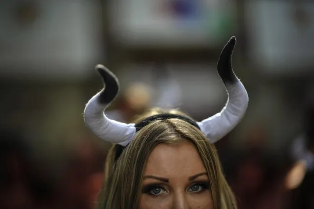 An activist wears bull horns during a protest against bull runs beside the bull ring a few days ahead to beginning the famous San Fermin Fiestas, in Pamplona northern Spain, Saturday, July 4, 2015. On July 6, the San Fermin festival will begin with the “txupinazo”, the opening ceremony with people participating in bull runs, music and dance, through the old street of the city. (Photo by Alvaro Barrientos/AP Photo)