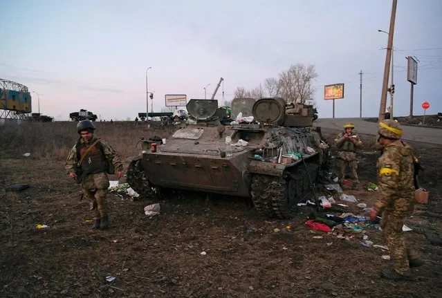 Ukrainian servicemen are seen next to a destroyed armoured vehicle, which they said belongs to the Russian army, outside Kharkiv, Ukraine on February 24, 2022. (Photo by Maksim Levin/Reuters)