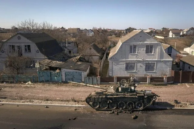 A destroyed tank sits on a street after battles between Ukrainian and Russian forces on a main road near Brovary, north of Kyiv, Ukraine, Thursday, March 10, 2022. (Photo by Felipe Dana/AP Photo)