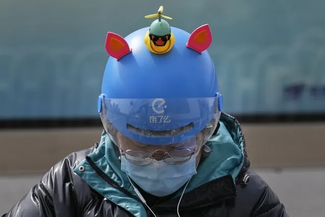 A delivery person for Chinese online food delivery platform Ele.me displays a rubber duck on her helmet on Wednesday, March 16, 2022, in Beijing. China's government tried Wednesday to reassure jittery investors by promising support for its struggling real estate industry, internet companies and entrepreneurs after regulatory crackdowns caused stock prices to plunge. (Photo by Ng Han Guan/AP Photo)