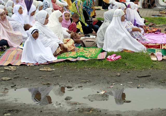 Muslim women and children are reflected on a puddle as they await the start of their morning prayer at a park in a slum area in Tondo, metro Manila July 17, 2015. (Photo by Romeo Ranoco/Reuters)