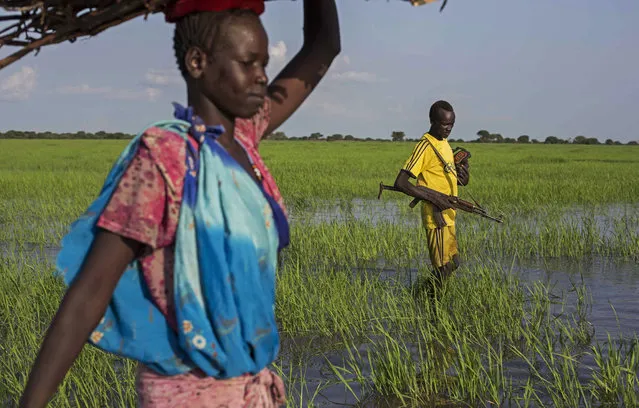 An armed youth walks through a river as he comes back home in the Yuai village, Uror county, Jonglei state in South Sudan on July 24, 2013 after fighting against the rebel group of Yau Yau in Pibor county, South Sudan. (Photo by Camille Lepage/AFP Photo)