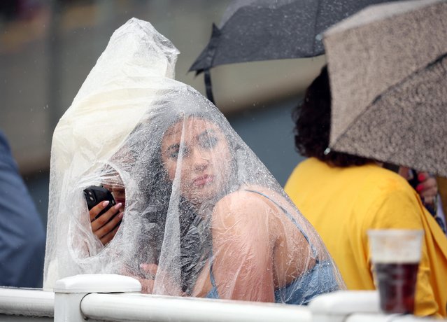 General view as racegoers shield themselves from the rain on Ladies Day at Aintree Racecourse in Liverpool, Britain on April 14, 2023. (Photo by Phil Noble/Reuters)