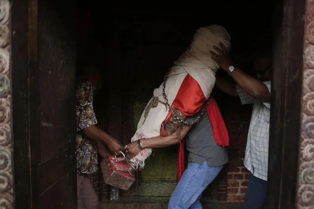 In this April 20, 2017, photo, members of the Chitrakar team of artists carry the statue of Rato Machindranath for painting and repairs in Machindra Bahal in Lalitpur, Nepal. The wide-eyed statue of Machindranath is made from red-painted clay, decorated with gold ornaments and kept under lock and key for months until it is brought out for the Rato Machindranath festival. The harvest festival, that preludes the monsoon season in Nepal, centers on a five-story high chariot that carries the deity in the capital Kathmandu. (Photo by Niranjan Shrestha/AP Photo)