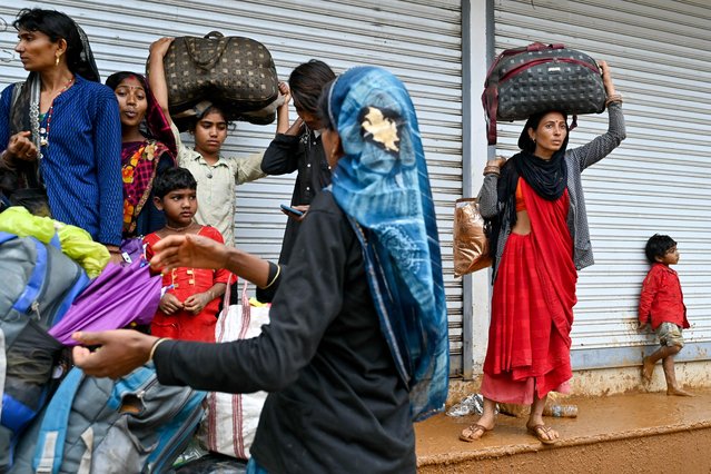 Tea plantation workers with their belongings, head to a relief camp after landslides in Wayanad on July 31, 2024. Relentless downpours and howling winds on July 31, hampered search for survivors of landslides that struck Indian tea plantations and killed at least 150 people, most believed to be labourers and their families. (Photo by Idrees Mohammed/AFP Photo)