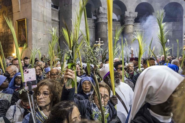 Christian pilgrims walk with palm fronds as they circle in a procession around the Edicule, traditionally believed to be the burial site of Jesus Christ, at the Church of the Holy Sepulchre in Jerusalem on April 2, 2023, Palm Sunday according to Catholics. (Photo by Menahem Kahana/AFP Photo)