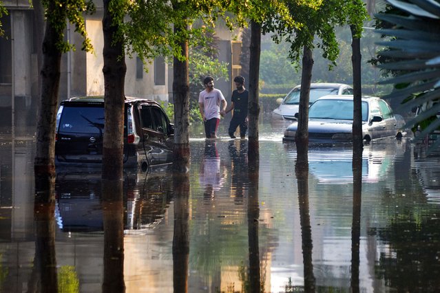 People wade through a flooded street after heavy rainfall in Faisalabad on August 5, 2024. (Photo by Ghazanfar Majid/AFP Photo)