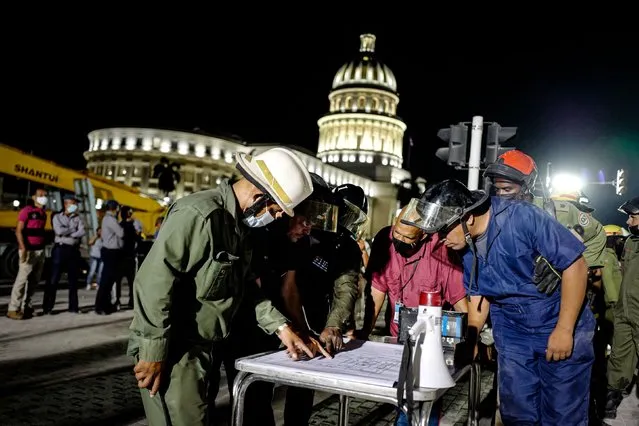 Firefighters look over a plan as rescue efforts continue after an explosion at the Saratoga Hotel, in Havana, on May 6, 2022. The death toll from a powerful explosion at a five-star hotel in central Havana climbed to 22 on May 6 with more than 50 people injured after a suspected gas leak, according to official tallies. (Photo by Adalberto Roque/AFP Photo)