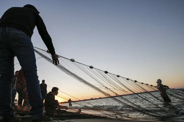 Palestinian fishermen retrieve their fishing nets back from the Mediterranean sea water at sunset in Gaza City on December 23, 2019. (Photo by Mohammed Abed/AFP Photo)