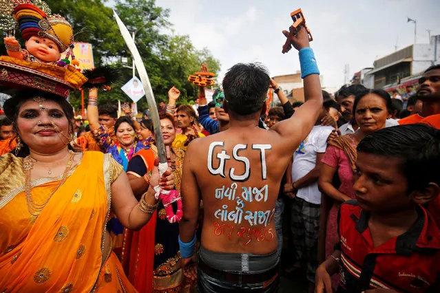 A Hindu devotee shows his painted back with a message stating “GST (Global Service Tax) – A new boon or a lasting burden?” ahead of the rollout of the new tax in India, during the annual Rath Yatra, or chariot procession, in Ahmedabad, June 25, 2017. (Photo by Amit Dave/Reuters)