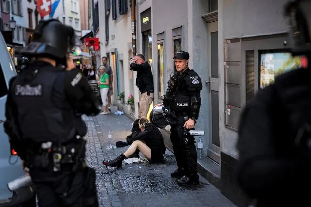 An injured young woman, center, is held by police officers next to an injured police officer in plain clothes, center back, after the police used pepper spray and rubber bullets against protesters during a demonstration against the World Economic Forum (WEF) in Zurich, Switzerland, Friday, May 20, 2022. (Photo by Michael Buholzer/Keystone via AP Photo)