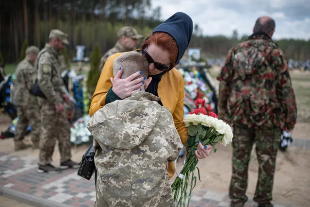 Alla, 42, hugs her son Savelii, 10, near the grave of Ihor Krotkih, husband of Alla and father to Savelii, on May 1, 2022 in Irpin, Ukraine. Ihor Krotkih was a Ukrainian soldier who was killed during the Russian occupation of Irpin. His older son Vladsylav, 21, and his brother Yurii, 48, were heavily injured in that battle, as they tried to evacuate him. The practice of visiting relatives' graves the week after orthodox Easter, a tradition referred to as Hrobki or Provody, held added poignancy as the country mourns the civilians and soldiers lost to the war with Russia. (Photo by Alexey Furman/Getty Images)