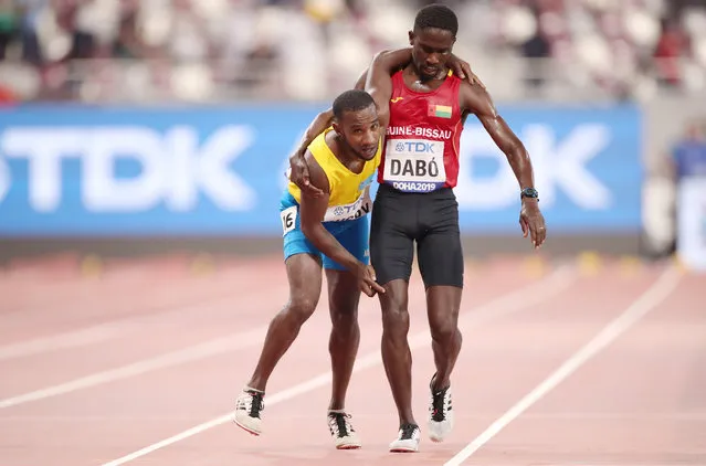 Guinea-Bissau's Braima Suncar Dabo assists Aruba's Jonathan Busby across the line of a men's 5000m heat at the World Athletics Championships in Doha, Qatar, Friday, September 27, 2019. (Photo by Christian Petersen/Getty Images)