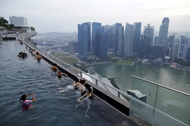 Tourists look at the skyline of the city from an infinity pool atop the 57 storey high Marina Bay Sands hotel in Singapore, in this July 10, 2015 file photo. Singapore-based wealth managers, already under pressure from a global move towards tax information sharing, face a more immediate threat as Asian countries including Indonesia and India look to chase undeclared money in the low-tax city state. (Photo by Edgar Su/Reuters)