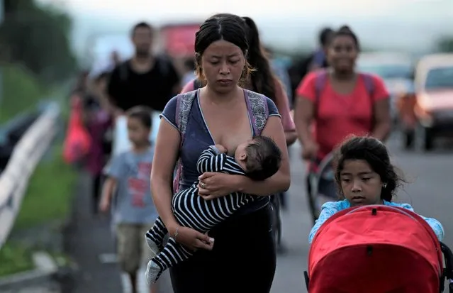 A woman breastfeeds her baby while she walks in a migrant caravan heading to Mexico City, in Pijijiapan, Mexico on November 4, 2021. (Photo by Daniel Becerri/Reuters)
