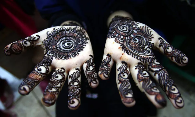 A Pakistani girl let the Henna tattoo dry ahead of the biggest Muslim Festival, Eid al-Fitr, to mark the end of Ramadan, in Karachi, Pakistan on July 5, 2016. Muslims around the world celebrate the holy month of Ramadan by praying during the night time and abstaining from eating and drinking during the period between sunrise and sunset. Ramadan is the ninth month in the Islamic calendar and it is believed that the Koran's first verse was revealed during its last 10 nights. (Photo by Shahzaid Akber/EPA)